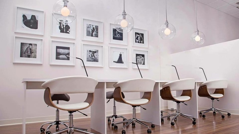 Custom-built manicure stations are accented by clean, white walls and decor.