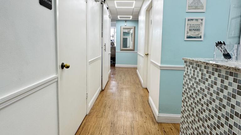 Hallway passing the front desk, patient bathroom, kitchen, private office, and leading to the operatories.