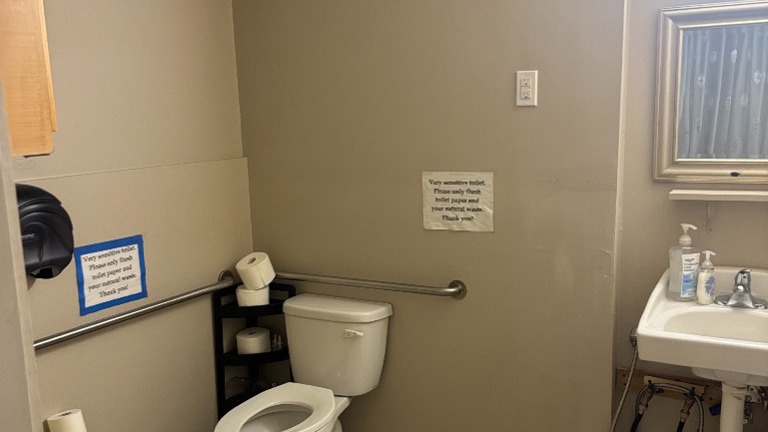 Restroom with toilet, sink, and mirror; equipped with grab bars.