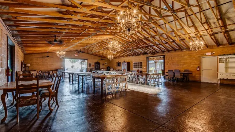 Elegant interior event space featuring soaring ceilings, chandeliers, and turnkey furnishings — averaging 30+ weddings annually.