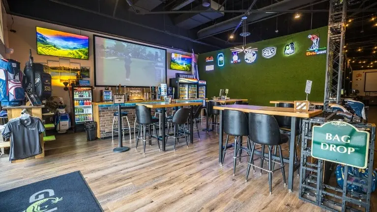 Main bar and viewing area with high-top seating, a large projection wall, and sports-themed décor — built for game-day crowds and league nights. Main bar and viewing area with high-top seating, a large projection wall, and sports-themed décor — built for game-day crowds and league nights.