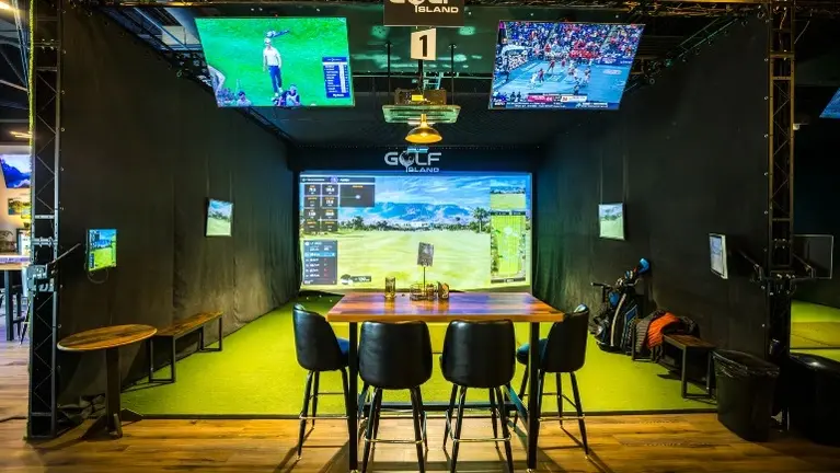 Private TrackMan simulator bay with screen, projector, and dedicated table seating — one of five throughout the venue. Private TrackMan simulator bay with screen, projector, and dedicated table seating — one of five throughout the venue.