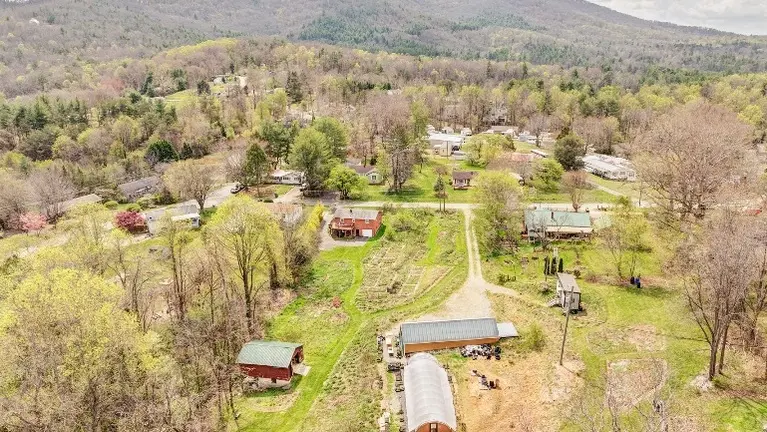 Property includes brick residence, passive solar greenhouse, hoophouse, barn and tiny house.