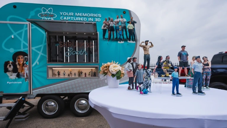 Mobile booth and 3D printed hyperealistic figurines on display at an outdoor event Mobile booth and 3D printed hyperealistic figurines on display at an outdoor event