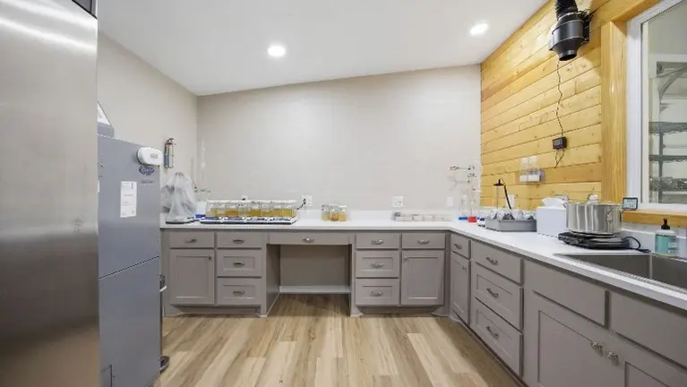 Dedicated prep and packaging room — commercial stainless steel work tables, Carrier HVAC, inline exhaust ventilation, and LVP flooring. Built clean, built righ