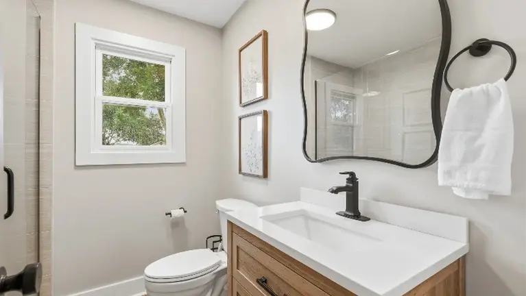 A well-appointed bathroom features a wood vanity, sleek black fixtures, and a large mirror for guests to get ready in comfort. A well-appointed bathroom features a wood vanity, sleek black fixtures, and a large mirror for guests to get ready in comfort.