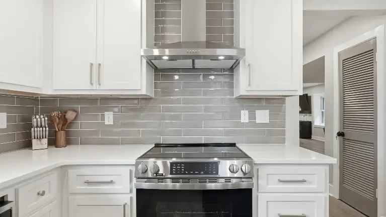 A sleek stainless range and vent hood anchor the kitchen, backed by a subway tile backsplash that ties the whole space together. A sleek stainless range and vent hood anchor the kitchen, backed by a subway tile backsplash that ties the whole space together.