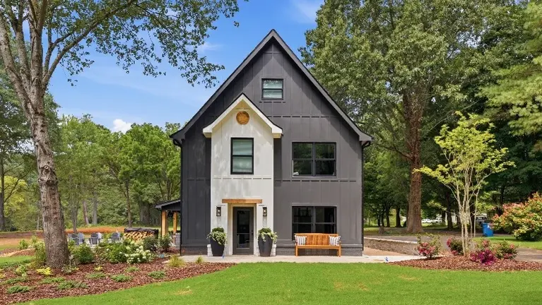 The farmhouse's black Hardie siding, crisp white trim, and warm cedar accents give it a polished curb appeal, with a covered patio, hot tub, and fire pit set u The farmhouse's black Hardie siding, crisp white trim, and warm cedar accents give it a polished curb appeal, with a covered patio, hot tub, and fire pit set u