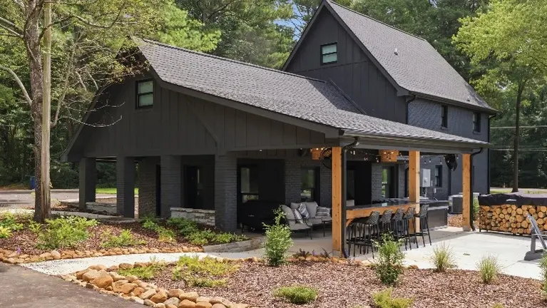The farmhouse's black Hardie siding, crisp white trim, and warm cedar accents give it a polished curb appeal, with a covered patio, hot tub, and fire pit set u The farmhouse's black Hardie siding, crisp white trim, and warm cedar accents give it a polished curb appeal, with a covered patio, hot tub, and fire pit set u