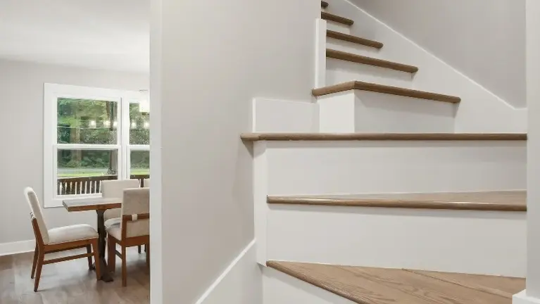 A wood-and-white staircase leads to the next level, with a small seating nook tucked just beside it. A wood-and-white staircase leads to the next level, with a small seating nook tucked just beside it.