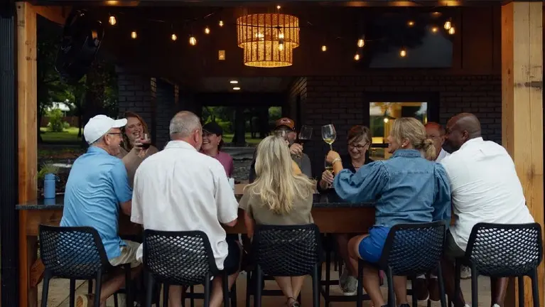 A group of guests gathers around the indoor/outdoor bar, which comfortably seats a crowd for drinks and casual evening gatherings. A group of guests gathers around the indoor/outdoor bar, which comfortably seats a crowd for drinks and casual evening gatherings.