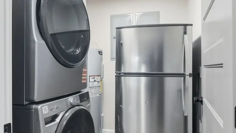 A stacked washer and dryer sit conveniently next to the refrigerator, keeping laundry within easy reach. A stacked washer and dryer sit conveniently next to the refrigerator, keeping laundry within easy reach.