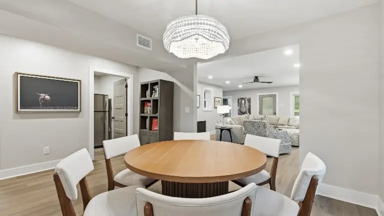 An open-concept living and dining area brings guests together around a round table, with a TV and built-in shelving close by. An open-concept living and dining area brings guests together around a round table, with a TV and built-in shelving close by.
