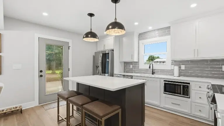 The kitchen's center island seating and door to the outside make it an easy spot for guests to grab a bite and head straight out to the patio. The kitchen's center island seating and door to the outside make it an easy spot for guests to grab a bite and head straight out to the patio.
