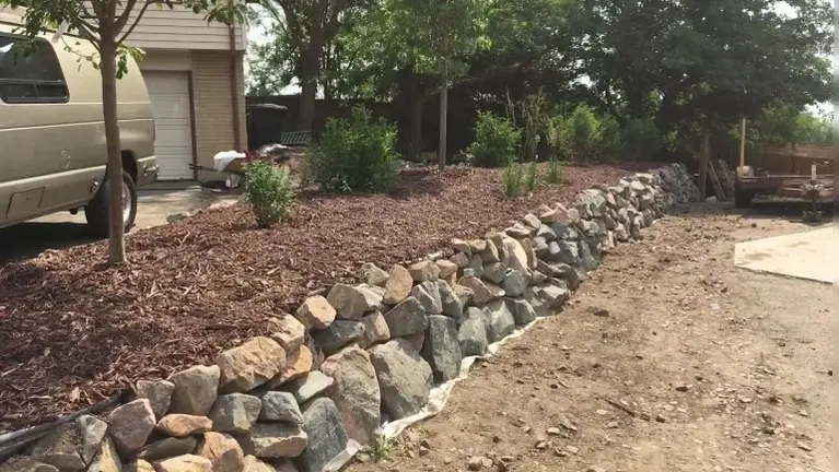 Landscape design with , dry stack retaining wall, planting and mulch