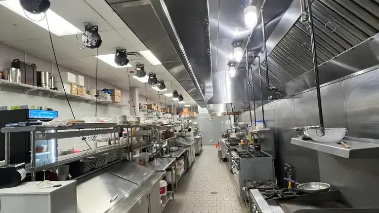 Fully equipped commercial kitchen with extensive stainless-steel prep and cooking line Fully equipped commercial kitchen with extensive stainless-steel prep and cooking line