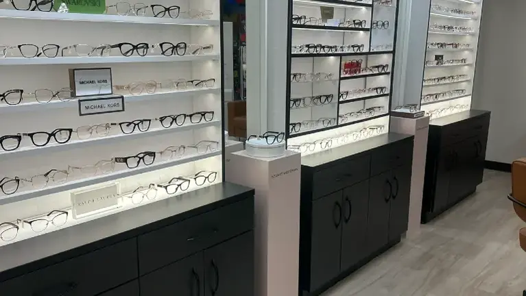 Extensive eyewear inventory displayed on modern illuminated shelving, featuring a wide selection of frames in a clean, professionally designed retail environme