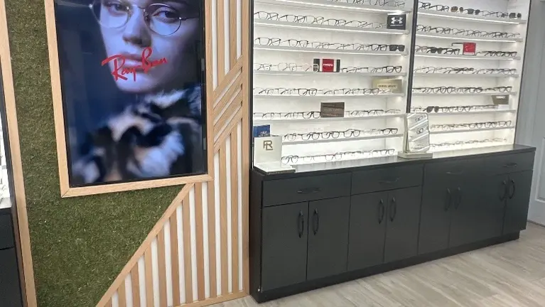 Large illuminated eyewear display featuring extensive frame inventory in a modern, professionally designed optical retail space.