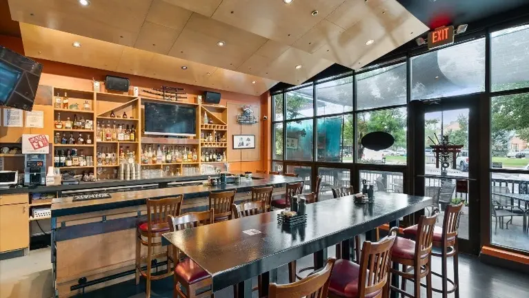 Bar and lounge seating with back-bar buildout, refrigeration, and storefront glazing.