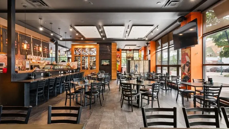 Dining room with sushi bar-height counter seating, pendant and track lighting, and street-facing window wall.